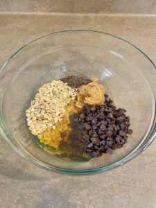 All ingredients shown in a mixing bowl for no bake peanut butter oat balls.
