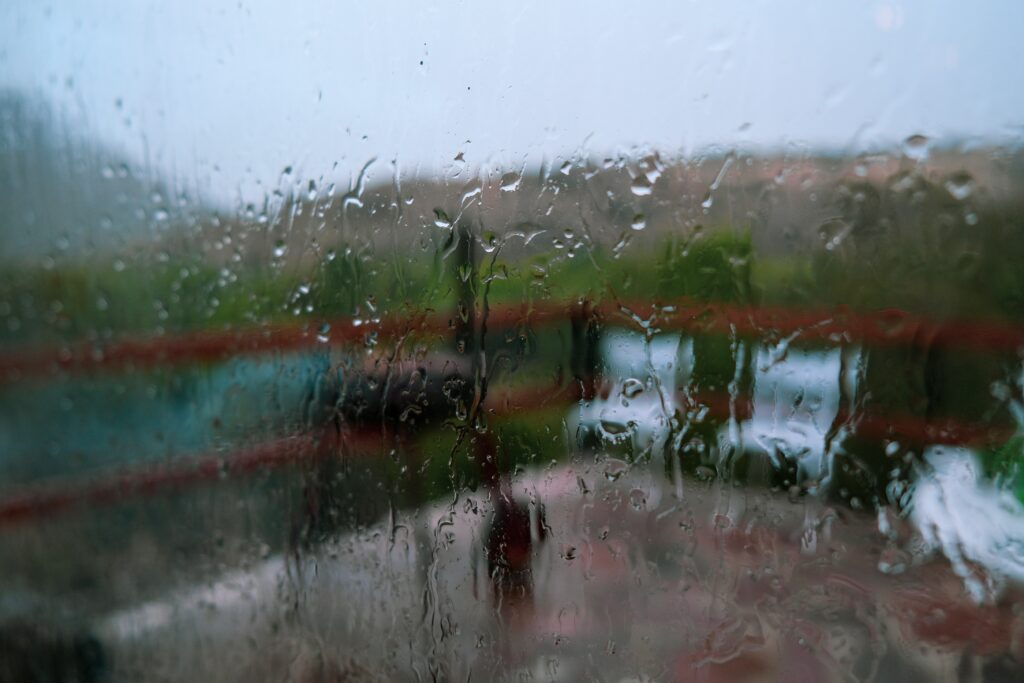 ADHD meal planning is easier when you check the weather first. Image is viewed through a window looking out on to a backyard deck while pouring rain outside.